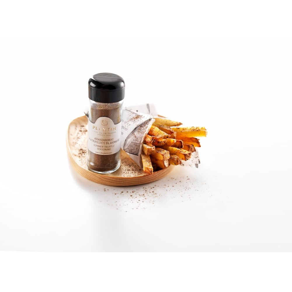 Flacon d’assaisonnement à la truffe d’été Plantin présenté aux côtés de frites dorées servies dans un cornet en papier. Le produit est disposé sur un plateau en bois avec un léger saupoudrage d’assaisonnement, dans une mise en scène gourmande et épurée sur fond clair.