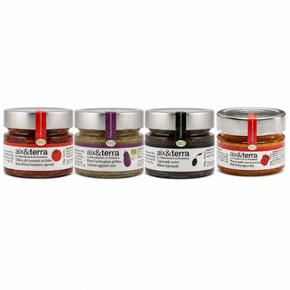 Sélection de tartinables bio Aix & Terra présentée en pots en verre, comprenant une crème de tomates séchées, un caviar d’aubergines grillées, une tapenade noire et une poivronnade au poivron rouge.
