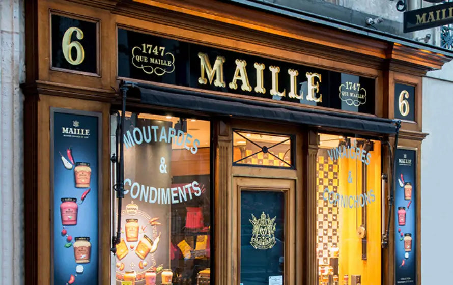 Façade de la boutique Maille Paris, spécialisée dans les moutardes, vinaigres et condiments, avec devanture noire et dorée emblématique de la Maison Maille.