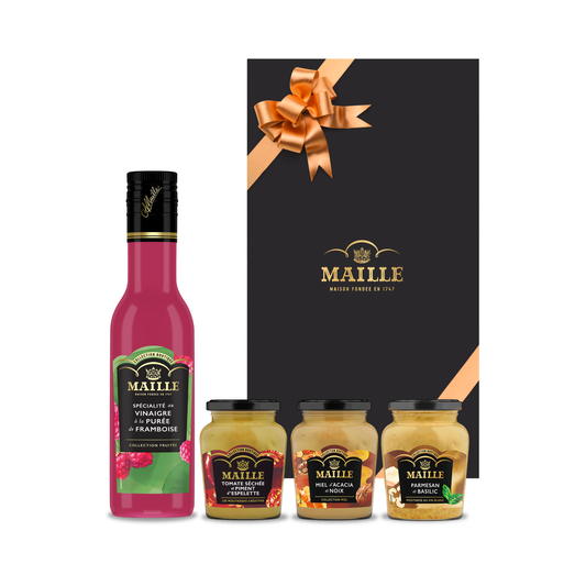 Coffret cadeau Maille composé d’un vinaigre à la purée de framboise et de trois moutardes aromatisées, présenté dans un élégant écrin noir orné d’un ruban doré.