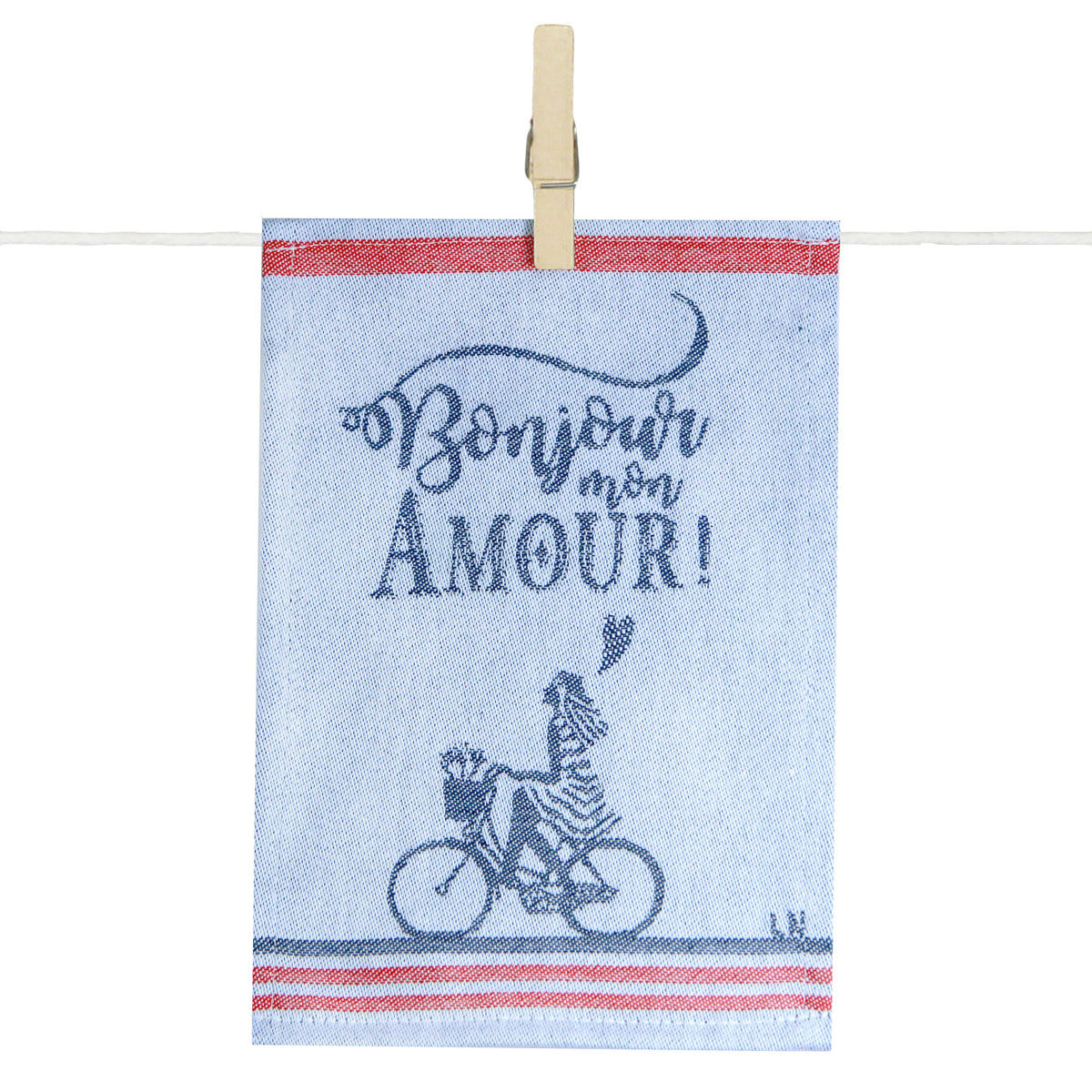 Para tapas de cuisine Maille illustré de l’inscription « Bonjour mon Amour ! » en bleu marine sur fond écru. Le visuel représente un personnage à vélo transportant une baguette et des fleurs dans un panier, encadré par des bandes rouges et bleues évoquant l’art de vivre à la française. Le torchon est présenté suspendu à une corde par une pince en bois.