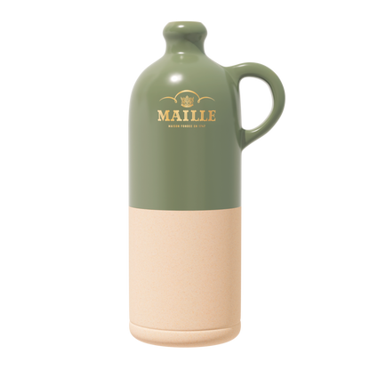 Cruche Maille en céramique bicolore avec partie supérieure vert sauge brillante et base beige naturel mate. Dotée d’une anse élégante et ornée du logo Maille doré sur la face avant, elle est présentée sur fond clair dans un style épuré et contemporain.