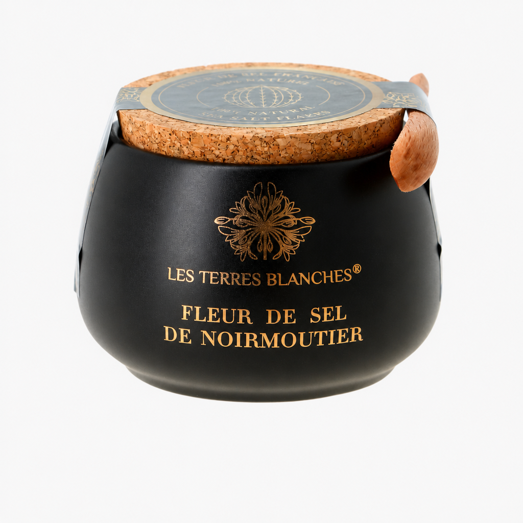 Pot de fleur de sel de Noirmoutier Les Terres Blanches présenté dans un élégant contenant en céramique bleu nuit. Le pot est doté d’un couvercle en liège naturel et d’une petite cuillère en bois intégrée. Le nom du produit est inscrit en lettres dorées sur la face avant.
