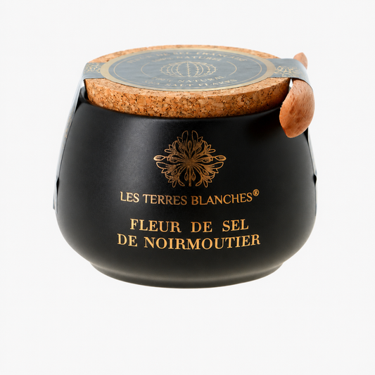 Pot de fleur de sel de Noirmoutier Les Terres Blanches présenté dans un élégant contenant en céramique bleu nuit. Le pot est doté d’un couvercle en liège naturel et d’une petite cuillère en bois intégrée. Le nom du produit est inscrit en lettres dorées sur la face avant.