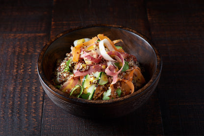 Salade gourmande de quinoa, légumes croquants et vinaigrette à la moutarde Maille, présentée dans un bol en bois sur une table aux tons chaleureux.